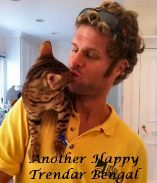 A man holding his cat while kissing him on the cheek.